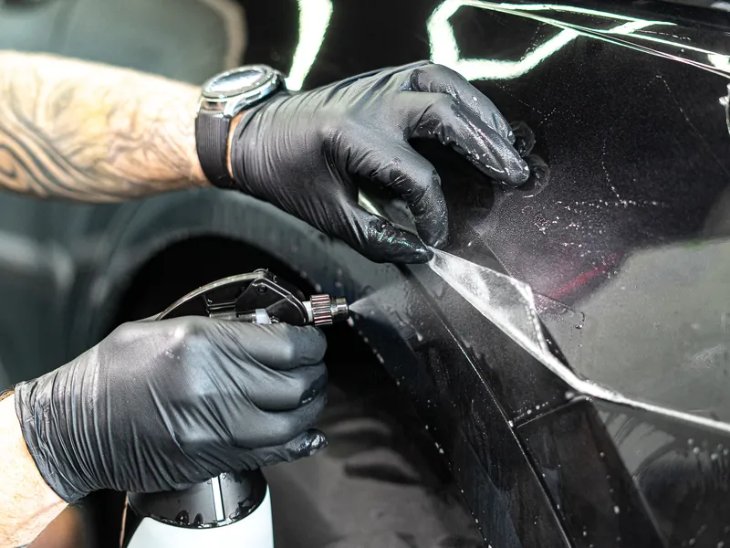 Detail okraje PPF fólie při aplikaci na černé Audi